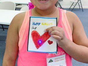 Young girl holds Fathers Day card with embedded circuit and LED light.